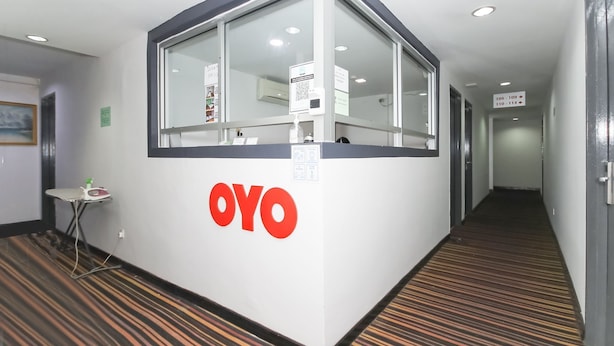 A reception area with a glass partition, a sign with the logo 'OYO', and a corridor with numbered doors. - OYO 90345 TM Hotel (Taman Melawati)