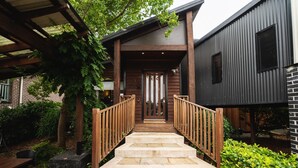 A wooden staircase leading to a house with a dark exterior and a brick wall.