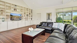 A modern living room with a leather sofa, a coffee table, and a built-in shelving unit with various decorative items.