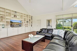 Una sala de estar moderna con un sofá de cuero, una mesa de centro y una estantería empotrada con varios objetos decorativos.