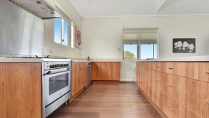 A kitchen with wooden cabinets, a stainless steel oven, and a window.
