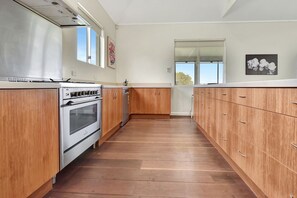 Una cocina con armarios de madera, un horno de acero inoxidable y una ventana.