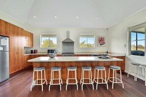 A modern kitchen with a central island, bar stools, and a stainless steel range hood.
