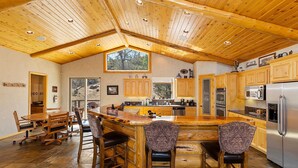A spacious kitchen with wooden cabinets, a large island with bar stools, and modern appliances.