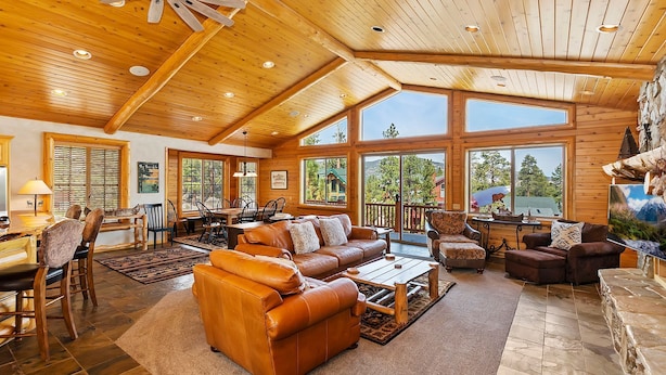 A spacious living area with a high ceiling, large windows, and a fireplace.