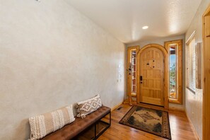 A hallway with a bench, wooden door, and a rug. - Rebel Ridge Retreat by Destination Big Bear : Gorgeous Mountain Views Backing to Nature Preserve in Eagle Mountain Estates! 2 Master Suites! Hot Tub! Pet Friendly! (Big Bear Lake)