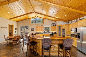 Une cuisine spacieuse avec des meubles en bois, un grand îlot central doté de tabourets, et une vue par la fenêtre.