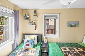 A bedroom with a bed, a nightstand, a window with curtains, a ceiling fan, and wall decorations. - Window Wonderland by Destination Big Bear : Custom Luxury Built Near the Lake! Breathtaking Lake Views! Gameroom! Hot Tub! (Big Bear Lake)