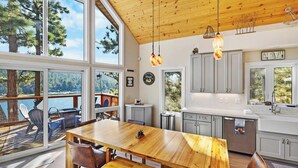A spacious kitchen with wooden cabinetry, a large island, and a view of a lake.