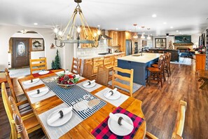 A spacious kitchen with wooden cabinets, a central island, and a dining area with a long table set for a meal.