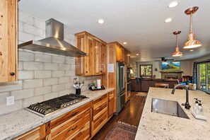 Enjoy cooking in this well-equipped kitchen with a range hood, refrigerator, and granite countertop.