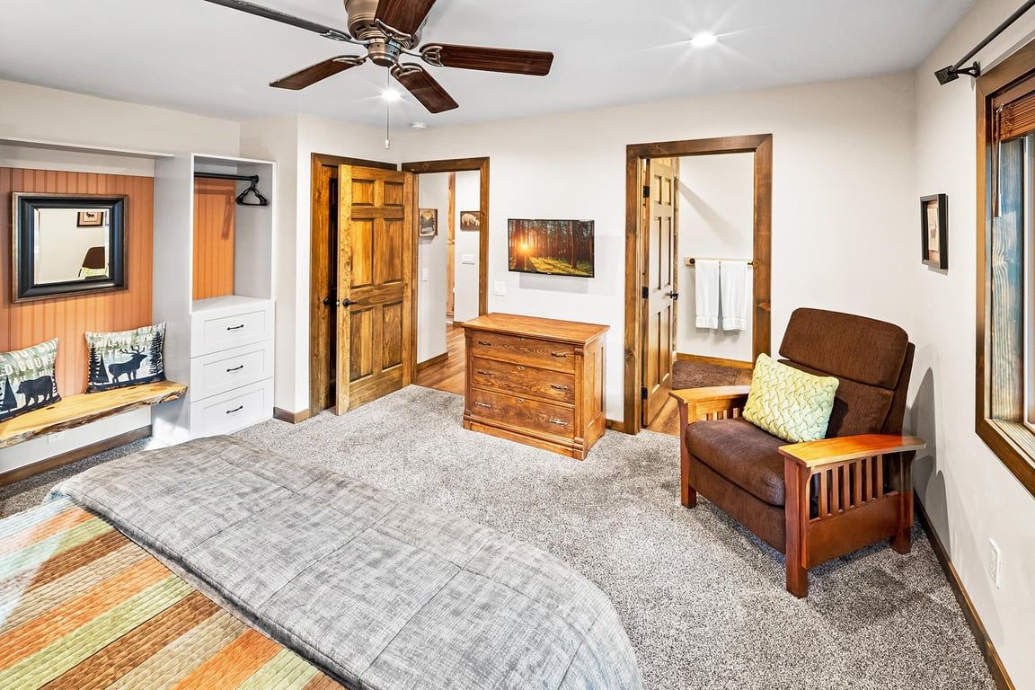 A bedroom with a bed, a chair, a dresser, and a ceiling fan.