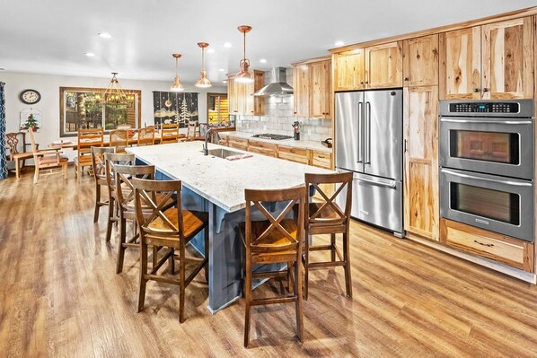 A modern kitchen with wooden cabinets, stainless steel appliances, and a central island with seating.
