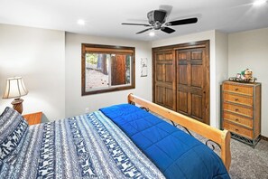 A bedroom with a bed, a wooden wardrobe, a window, and a ceiling fan. - Flapjacks and Lumberjacks by Destination Big Bear : Walk to the Lake in Boulder Bay! Theater Room! Foosball! (Big Bear Lake)