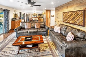 A spacious living room with a leather sofa, a coffee table, and a patterned rug.