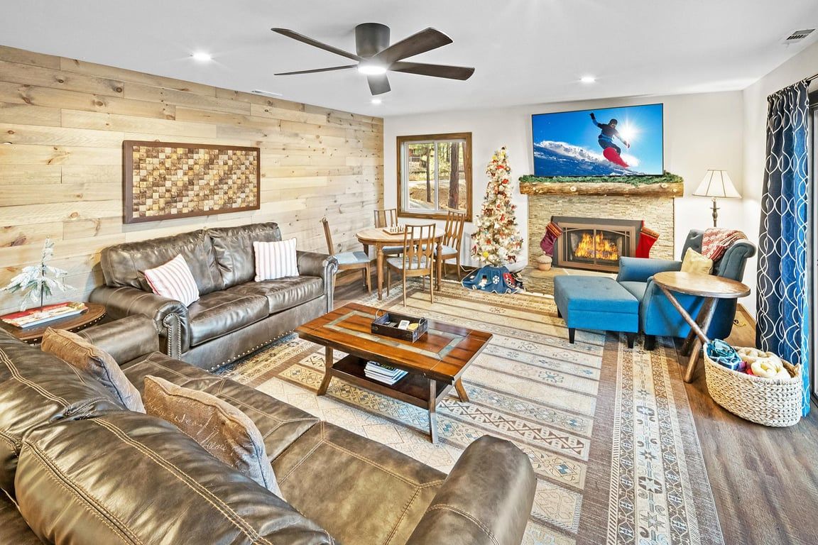 Una sala de estar con chimenea, ventilador de techo y un árbol de Navidad.