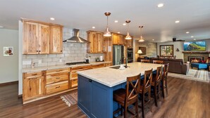 A spacious kitchen with wooden cabinets, a central island, and pendant lighting.