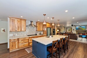 Enjoy cooking and dining in this well-equipped kitchen with a central island, stove, and large flat-screen TV.