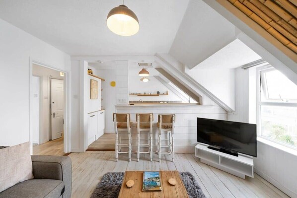 A modern apartment with a TV, a coffee table, and a bar area.