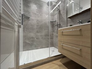 A modern bathroom with a glass shower enclosure, a wooden vanity, and a marble-tiled shower wall. - Cozy apartment with balcony, ski-in/ski-out, Wi-Fi, pets allowed - Méribel (Méribel)