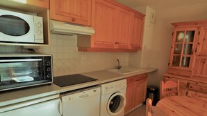A compact kitchen with a microwave, toaster, sink, and washing machine.