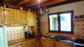 Une cuisine avec des meubles de rangement en bois, un grille-pain, un évier et une fenêtre avec des rideaux.
