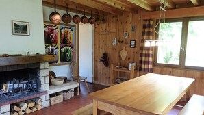Un intérieur rustique en bois, avec une cheminée, des bancs en bois et une longue table.