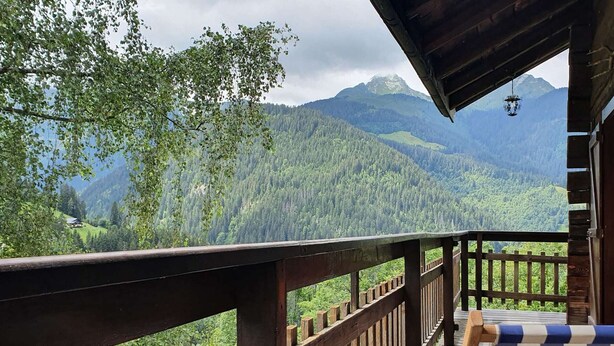 Une terrasse en bois offrant une vue sur une chaîne de montagnes boisée.