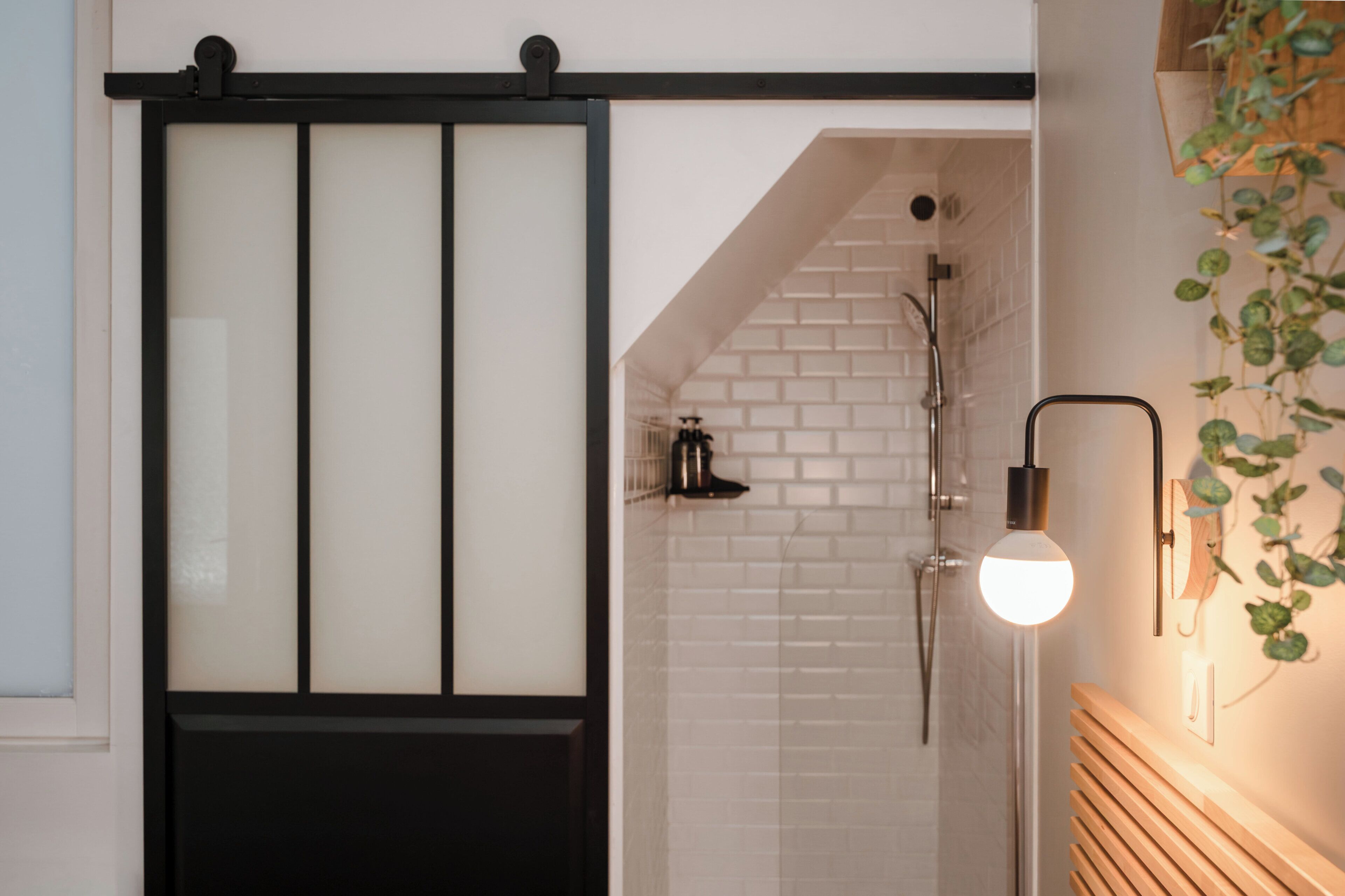 Un baño con ducha, toallero e iluminación en la pared.