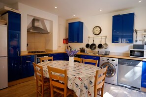A compact kitchen with blue cabinets, a stove, a microwave, and a washing machine.