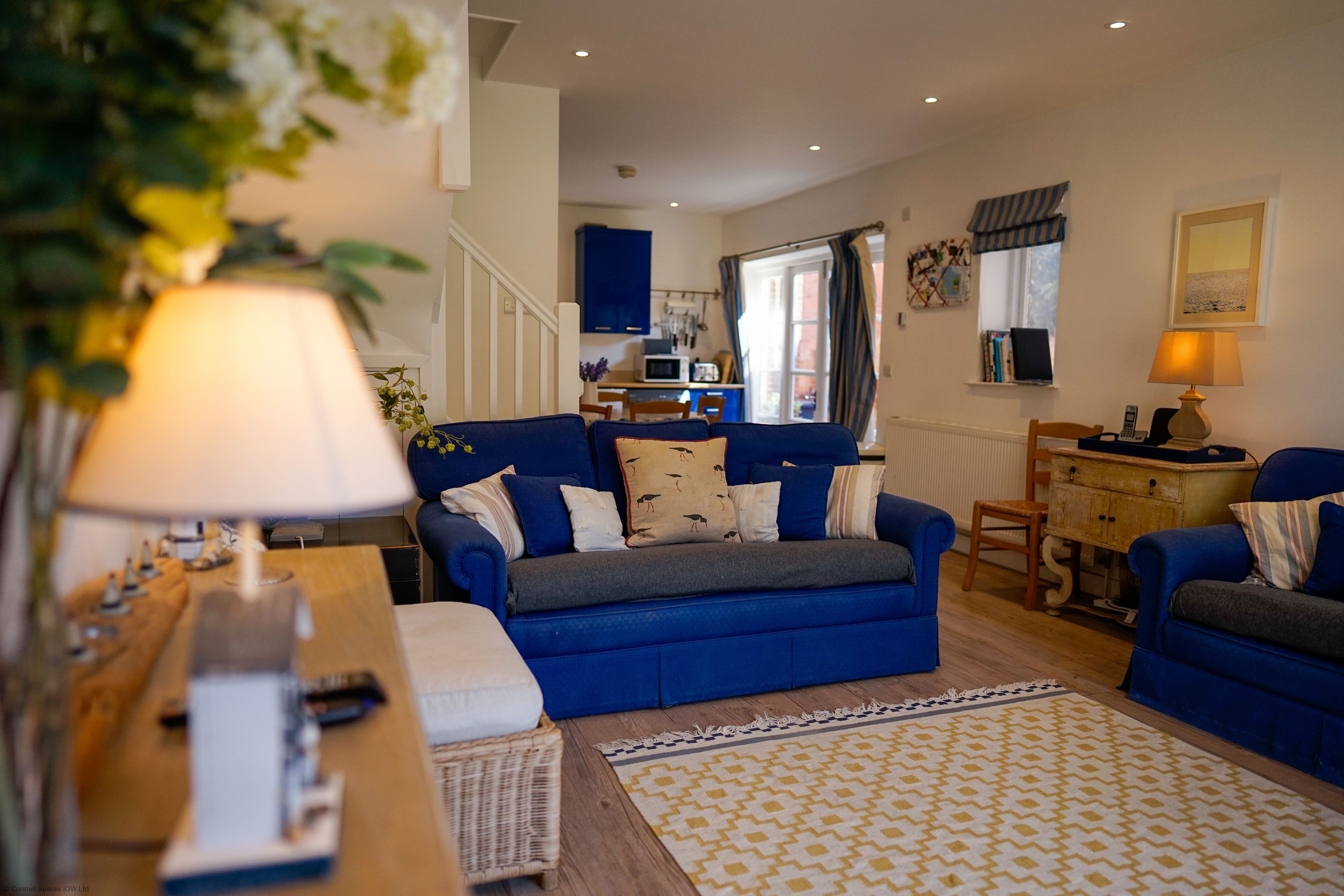 A cozy living room with a blue sofa set, a wooden coffee table, and a patterned rug.