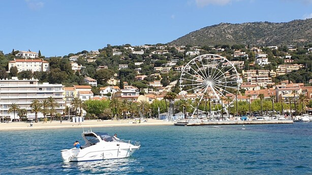 Une ville côtière dotée d’une grande roue, d’un port de plaisance avec des bateaux et d’une plage.