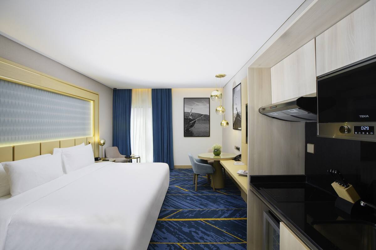 Une chambre d’hôtel dotée d’un grand lit, d’un bureau, d’une kitchenette et d’un coin repas.