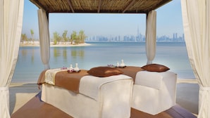 A luxurious bed with a city view, a thatched roof, and a serene beach setting. - Anantara World Islands Dubai Resort (Dubai)