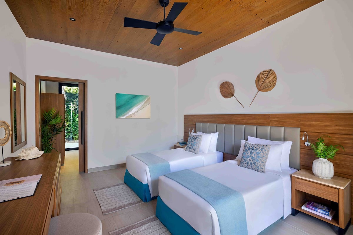 Une chambre d’hôtel moderne avec deux lits, un plafond en bois et une grande fenêtre.