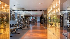 A modern gym with various exercise equipment, wooden flooring, and glass walls. - SVS: Modern 3BD Strip View Condo | 1,000+ sqft | Sleeps 12 | Jockey Club (Las Vegas)