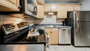 A modern kitchen with stainless steel appliances, wooden cabinets, and a tiled backsplash. - SVS: Modern 3BD Strip View Condo | 1,000+ sqft | Sleeps 12 | Jockey Club (Las Vegas)