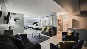 A modern living room with a sofa, armchairs, a coffee table, and a bed in the background. - SVS: 3BD/3BA Penthouse | 1,600 sqft | Strip Views | Jockey Club (Las Vegas)
