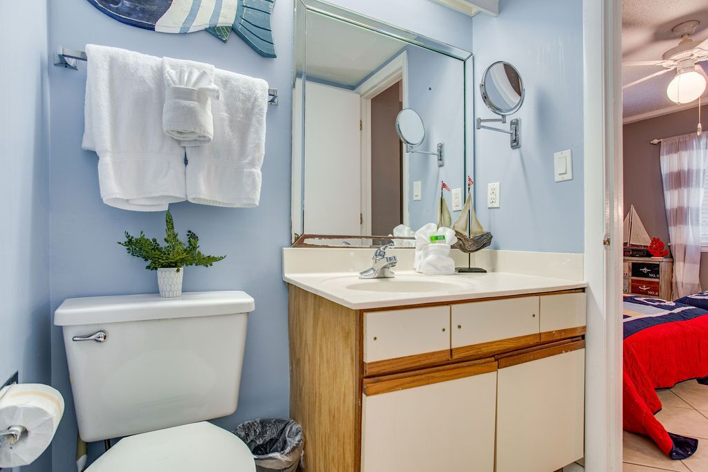 Une salle de bain équipée de toilettes, d’un lavabo, d’un miroir et d’un porte-serviettes.
