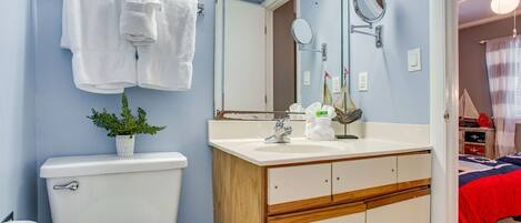 Une salle de bain équipée de toilettes, d’un lavabo, d’un miroir et d’un porte-serviettes.
