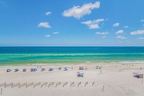 A beach with clear blue water, umbrellas, and a sandy shore.