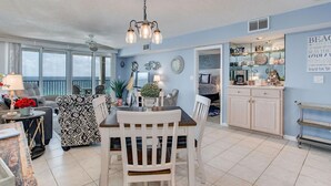 A spacious living area with a dining table, chairs, and a ceiling fan. There is a kitchen area with cabinets and a countertop. - Orange Beach Gulf-View 2BR • Sleeps 8 • Wet Bar • Kid-Friendly • Pools • Boats (Orange Beach)