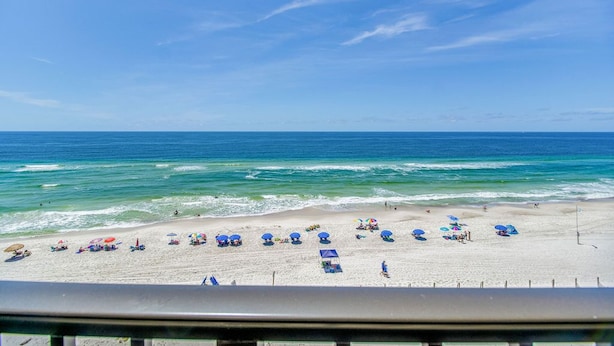 Ein Strand mit Sonnenschirmen und Menschen, ein klarer Himmel und das Meer.