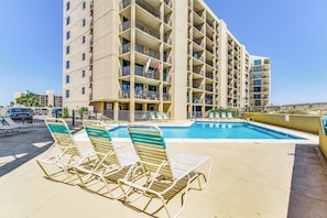 Un hôtel doté d’une piscine sur le toit, de plusieurs balcons et de chaises longues.