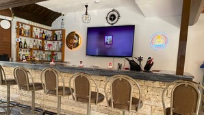 A bar area with stools, a TV, a clock, and a neon sign. - Ozay Apart Hotel (Marmaris)