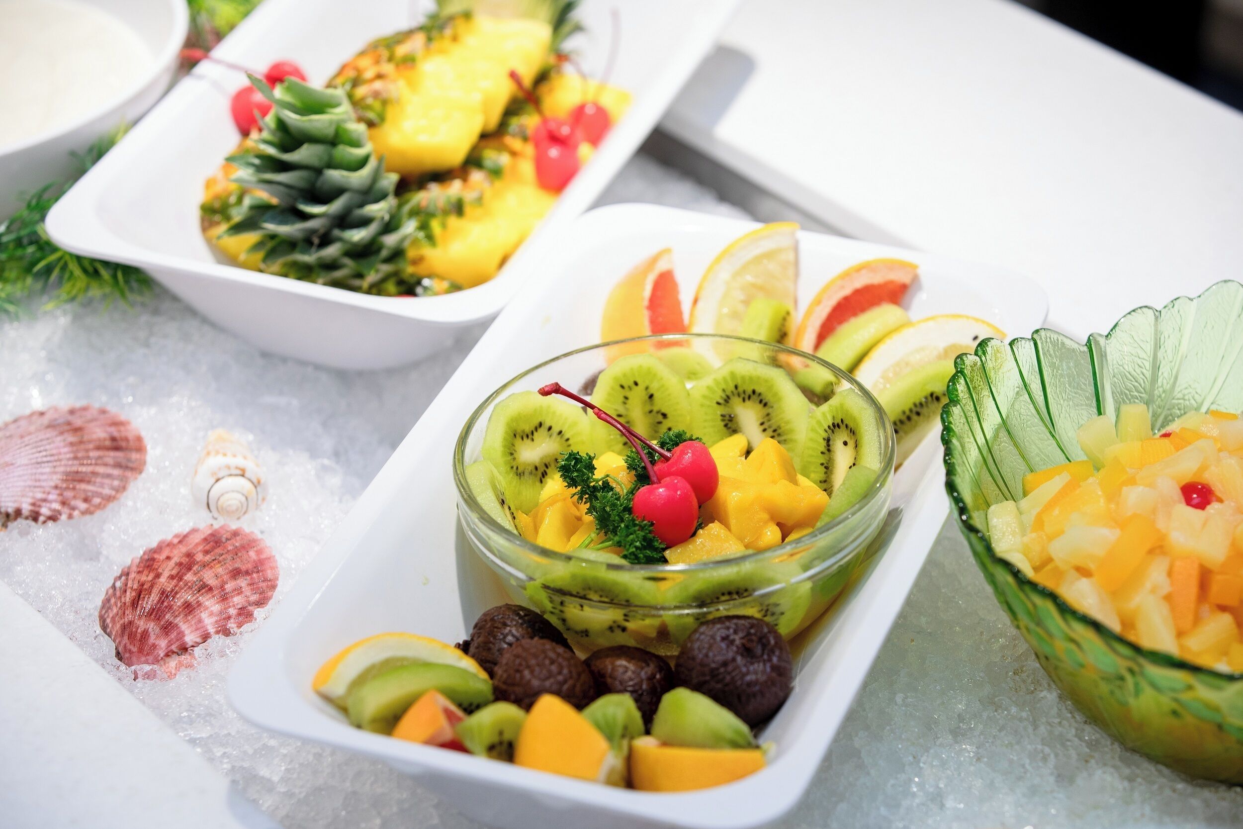 Three bowls of fruit on a table with ice.