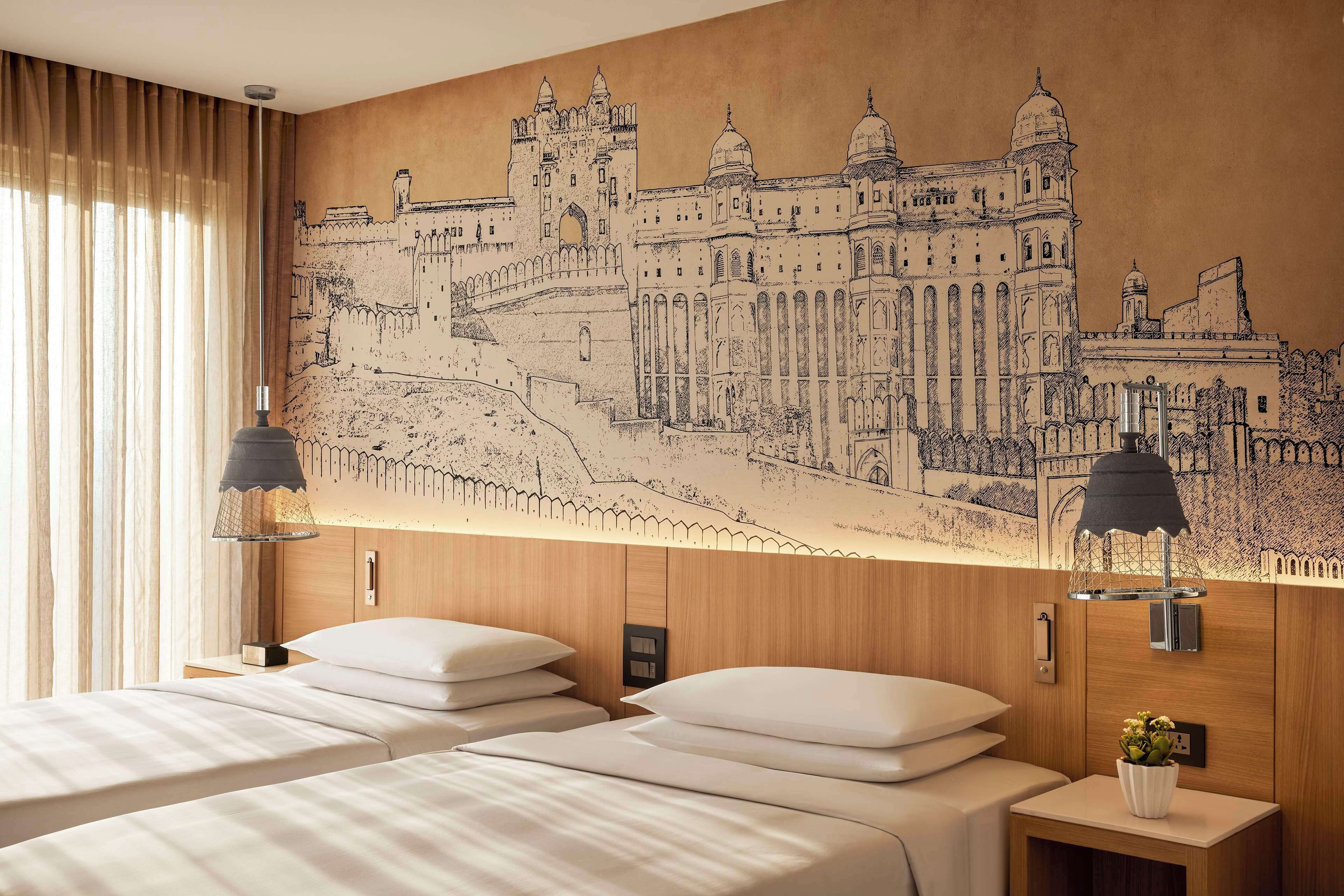 Una habitación de hotel con dos camas, un gran mural en la pared de un castillo y dos lámparas de noche.