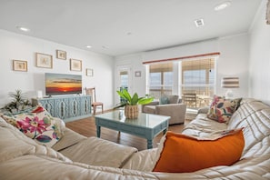A living room with a sofa, a coffee table, a TV, and a plant.
