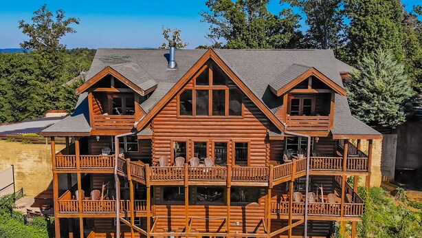 A multi-story log cabin with balconies, outdoor seating, and a scenic view. - Serenity Mountain Pool Lodge, Theater Room, Sleeps 42, Indoor Pool!!! (Sevierville)