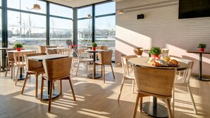 A modern cafe with large windows, wooden furniture, and a brick wall. - B&B HOTEL Epernay (Epernay)